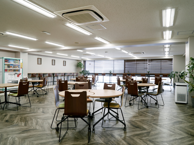 学生ラウンジ： 2024年に学生の意見を反映して全面リニューアル。自動販売機やコピー機を設置し、緑豊かな空間で飲食しながらくつろげる交流スペースです。